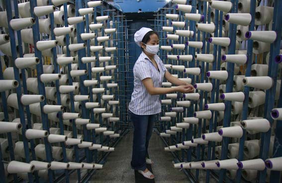 picture of a textile worker amidst cones of thread, silk?
